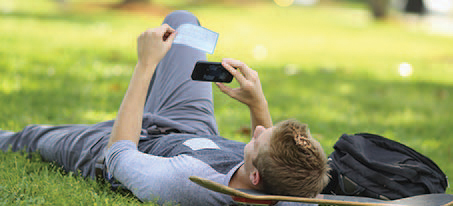 man laying in grass looking at phone